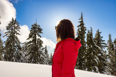 Rear view of woman standing by trees against sky