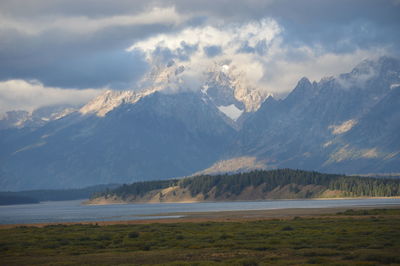 Scenic view of mountains and lake against cloudy sky