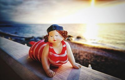 Boy sitting on toy at beach against sky