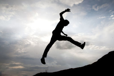 Low angle view of silhouette man jumping against sky during sunset