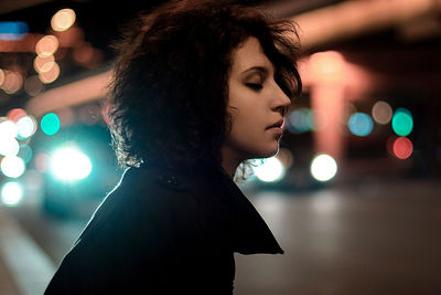 Portrait of young woman looking away at night