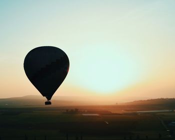 Hot air balloon flying over landscape against sky during sunset