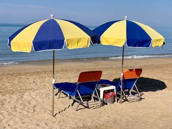 Deck chairs on beach against sea