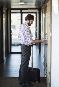 Side view of businessman opening hotel door with cardkey