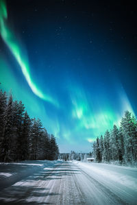 Snow covered road against sky at night during winter