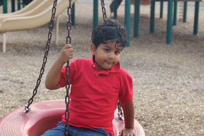 Boy sitting on swing at playground