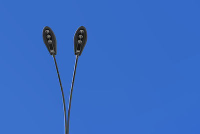 Low angle view of lighting equipment against blue sky