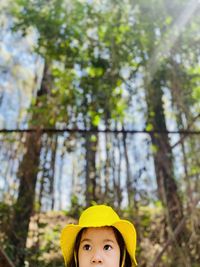 Portrait of young woman standing against trees