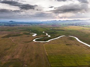 Scenic view of road amidst field against sky