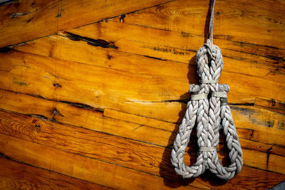 Close-up of rope tied on wood against wall