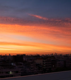 Cityscape against dramatic sky during sunset