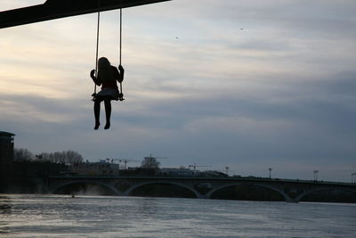 Rear view of man jumping on bridge against sky