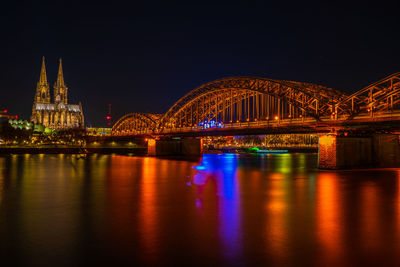 Illuminated bridge over river at night