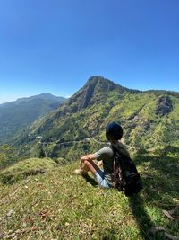 Rear view of woman sitting against mountain