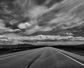 Empty road against cloudy sky