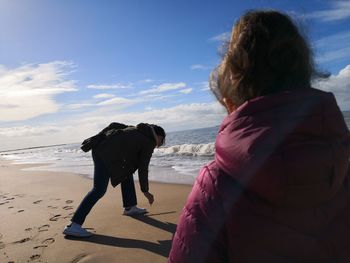 Rear view of dog on beach against sky