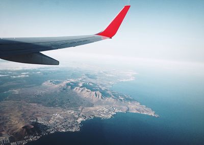 Aerial view of airplane flying over sea against sky