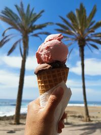 Close-up of hand holding ice cream cone on beach