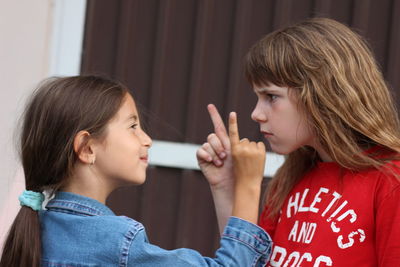 Sisters pointing while standing face to face