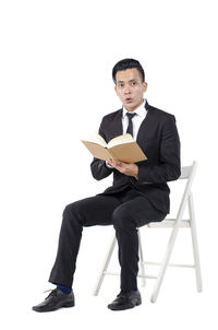 Portrait of young man sitting on seat against white background