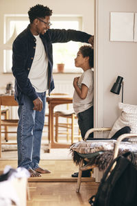 Father measuring height of son standing at doorway of home