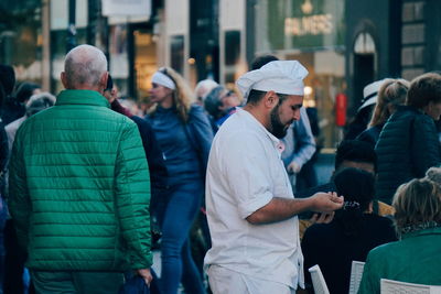 Rear view of people standing on street in city