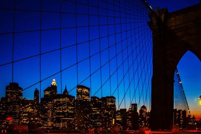 Low angle view of city lit up against blue sky