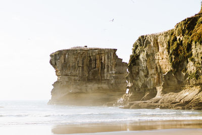 Scenic view of rock formation and sea against clear sky