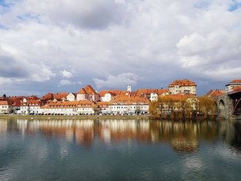 Houses at waterfront against cloudy sky