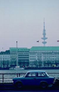 Cars on road by buildings against sky in city