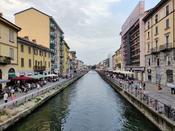 Canal amidst buildings in city against sky