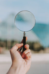 Close-up of hand holding magnifying glass