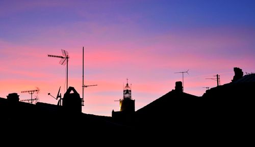 Low angle view of silhouette communications tower against sky during sunset