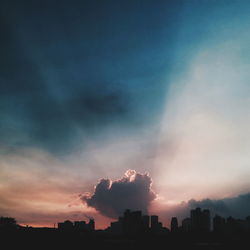 View of city against cloudy sky at sunset