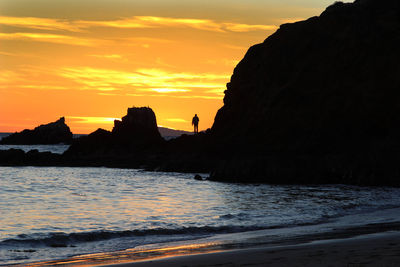 Silhouette of person standing on rock