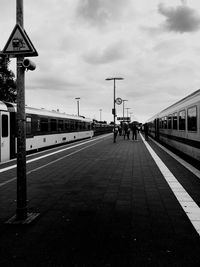 People on railroad station platform against sky