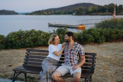 Happy loving caucasian couple sitting by the lake