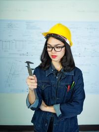 Young woman looking away while standing against wall