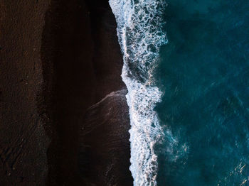 High angle view of waves splashing on rocks at shore