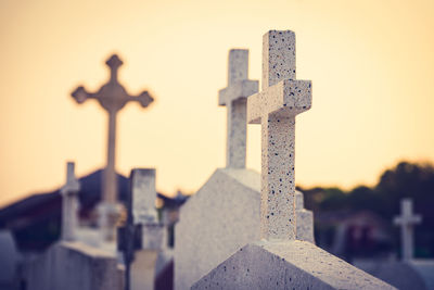 Close-up of cross at cemetery against sky