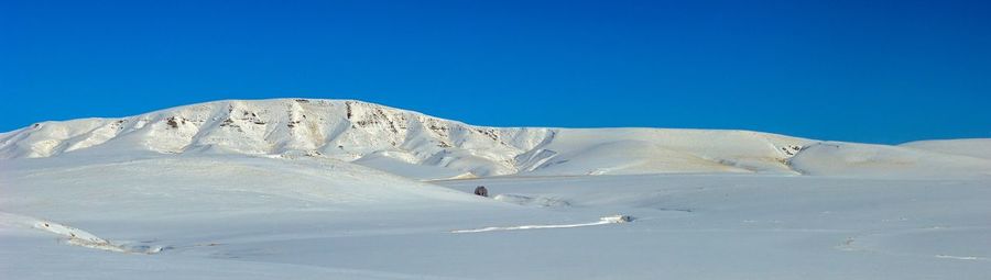 Scenic view of snowcapped mountains against clear blue sky