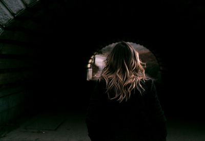 Rear view of woman with blond hair walking towards tunnel