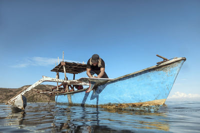 Fishing boat in sea against clear blue sky