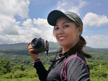 Portrait of smiling girl photographing against sky