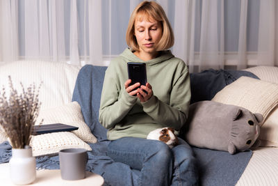 Young woman using phone while sitting at home