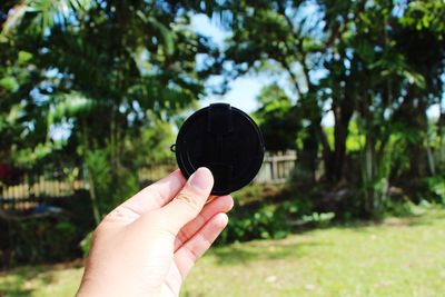 Close-up of hand holding black circle shaped object in park