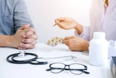 Midsection of doctor holding blister pack while discussing with patient at clinic