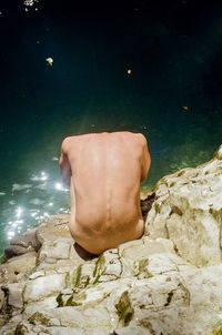 Rear view of shirtless man swimming in sea