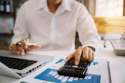 Midsection of man using laptop at office