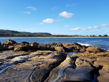 Rocks on beach against blue sky